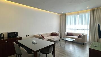 Ein modernes Wohnzimmer mit Esstisch, zwei Sofas, einem Couchtisch und einem Fernseher auf einem Schrank.