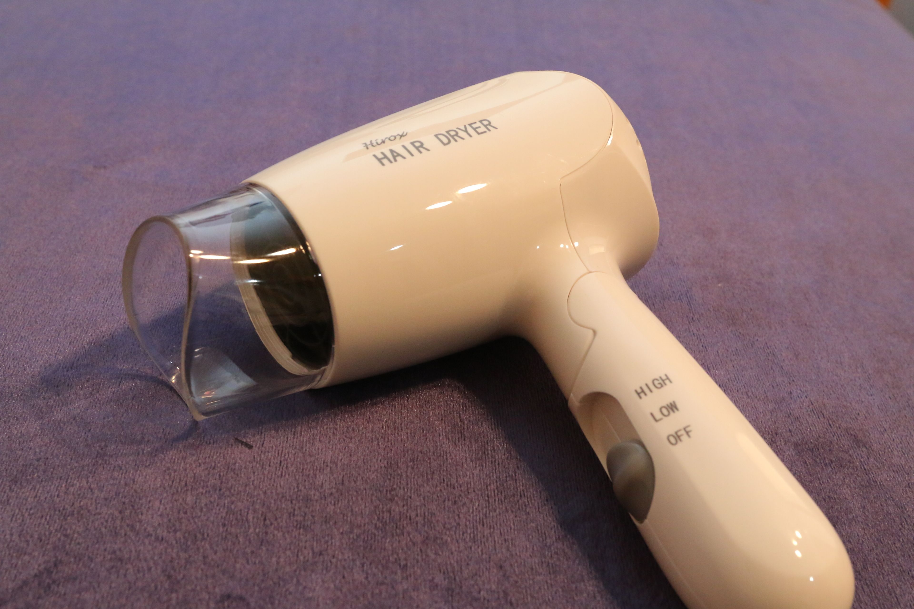 Um secador de cabelo com uma seção transparente e um botão de controle com as opções 'HIGH' e 'LOW'.
