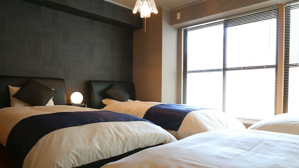 Ein Hotelzimmer mit zwei Betten, einem Nachttisch und einem Fenster mit Jalousien.