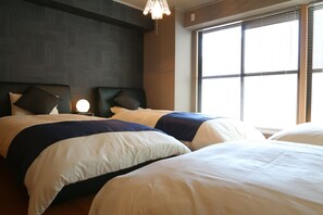 A hotel room with two beds, a nightstand, and a window with blinds.