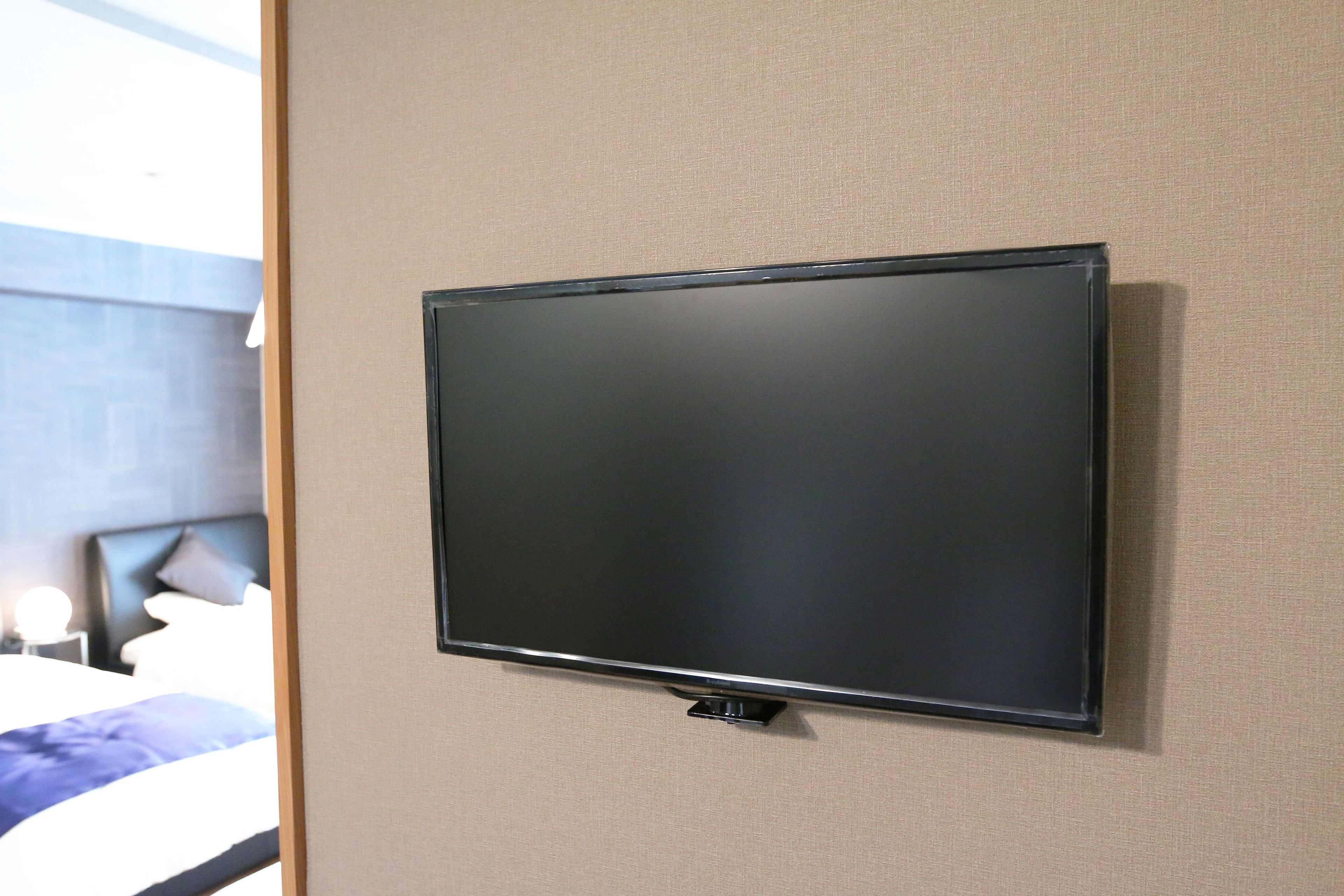 A flat-screen TV mounted on a beige wall in a hotel room.