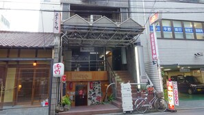Ein Gebäude mit einem Schild für ein Hotel, einer Treppe, die zum Eingang führt, und einem Fahrrad davor.