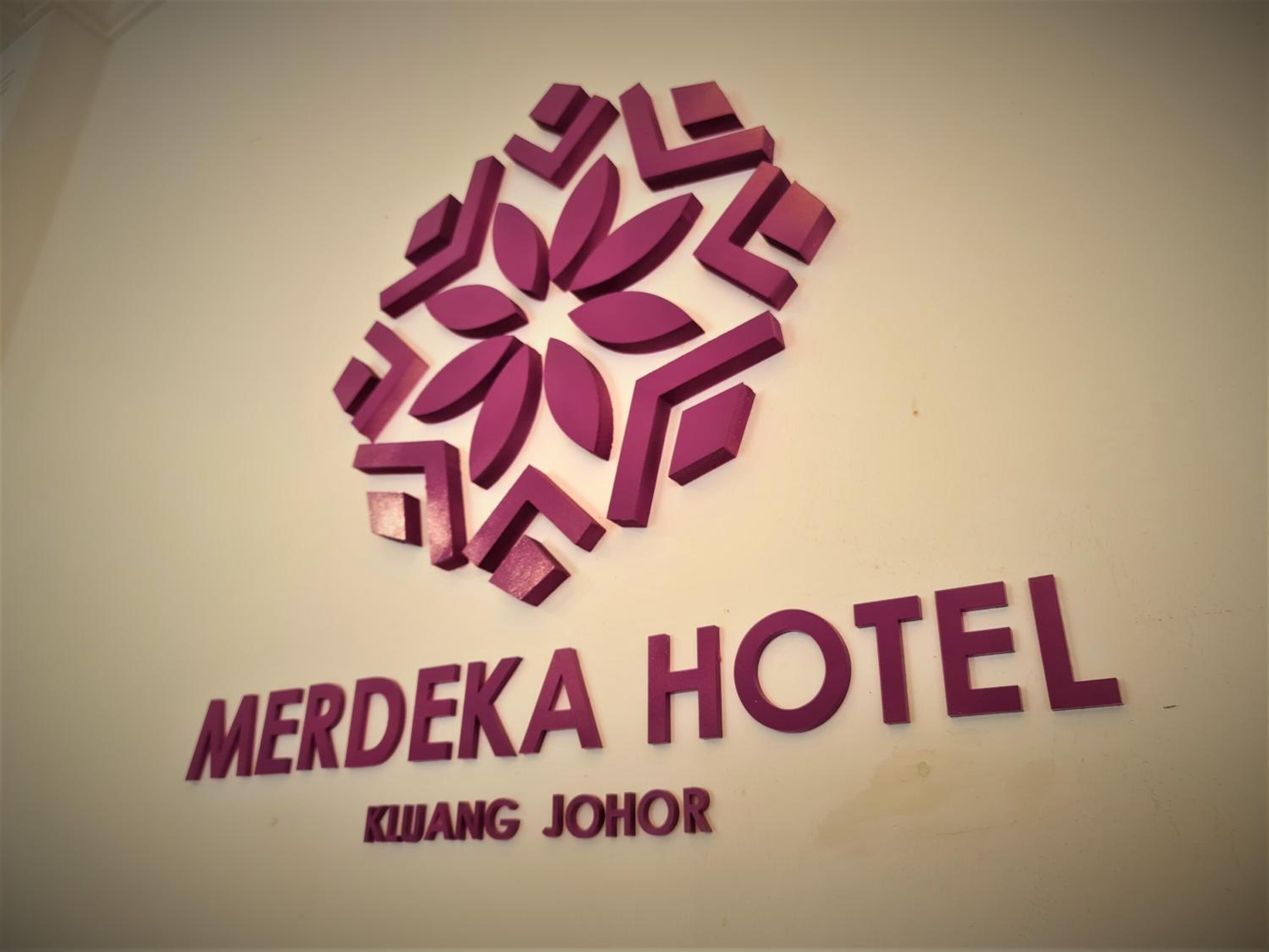 A sign for Merdeka Hotel with a stylized logo above the name.