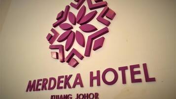 A sign for Merdeka Hotel with a stylized logo above the name.