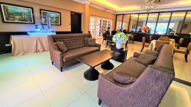 A hotel lobby with a brown sofa, a purple armchair, a coffee table, and a reception desk. - Merdeka Hotel (Kluang)