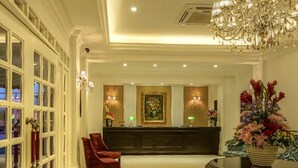 A hotel lobby with a reception desk, a chandelier, and a large window with a view of the outside. - Merdeka Hotel (Kluang)