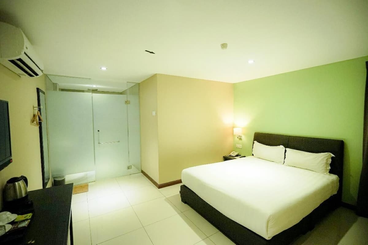 A hotel room with a bed, bedside table, lamp, and a wardrobe.