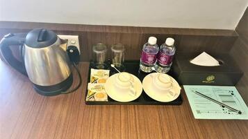 Organización de un minibars con cafetera, dos tazas, dos botellas de agua, una caja de pañuelos y un menú.