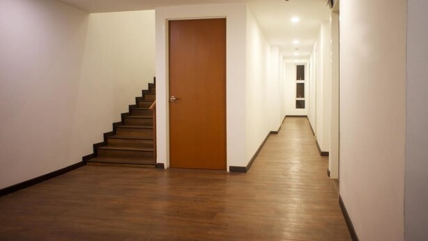 Un long couloir étroit, doté d’un plancher en bois et de murs blancs.