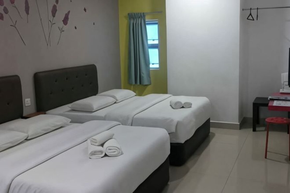 A hotel room with two beds, a desk, a chair, and a window with curtains.