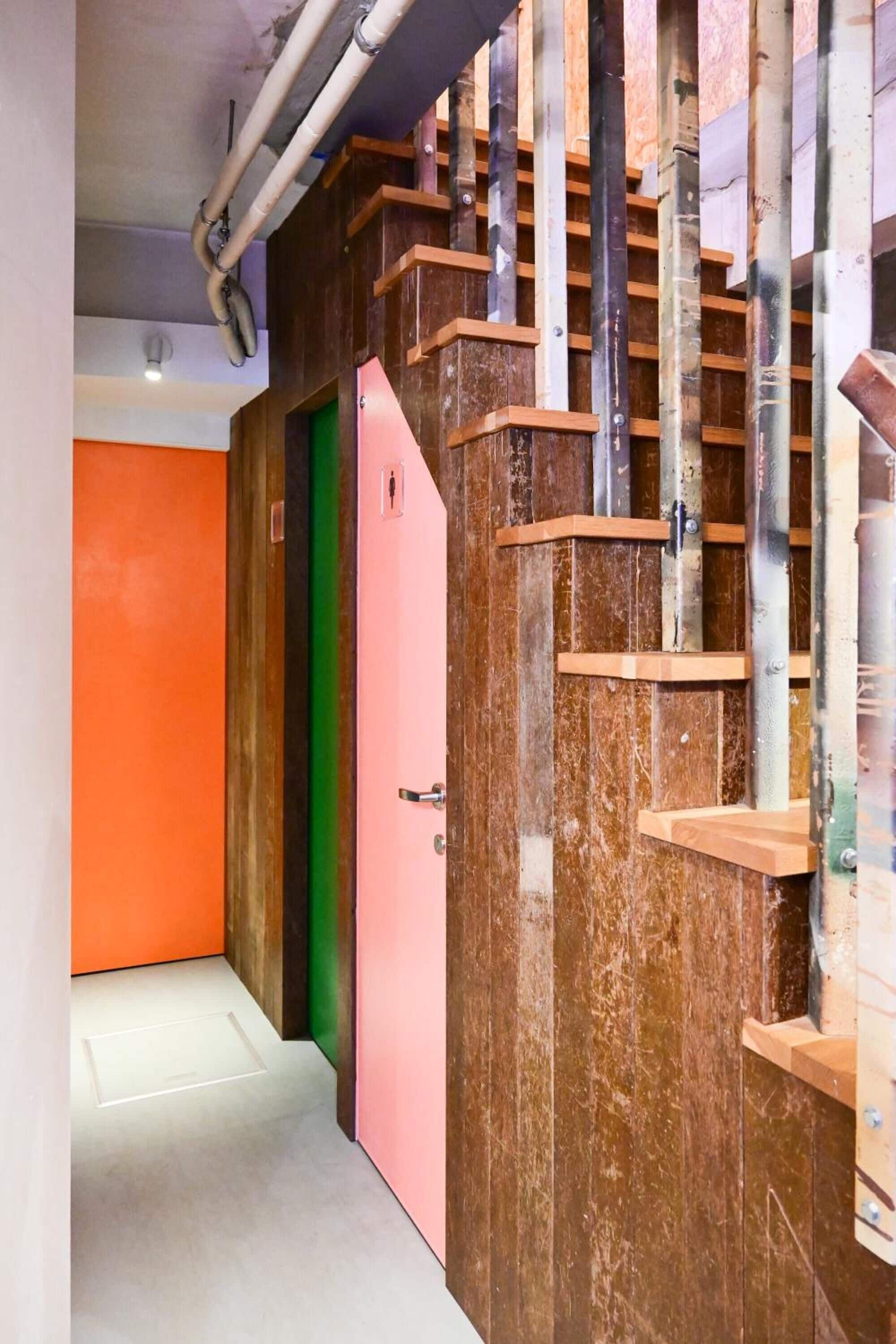 A staircase with wooden steps and metal railings, leading to a room with a green door.
