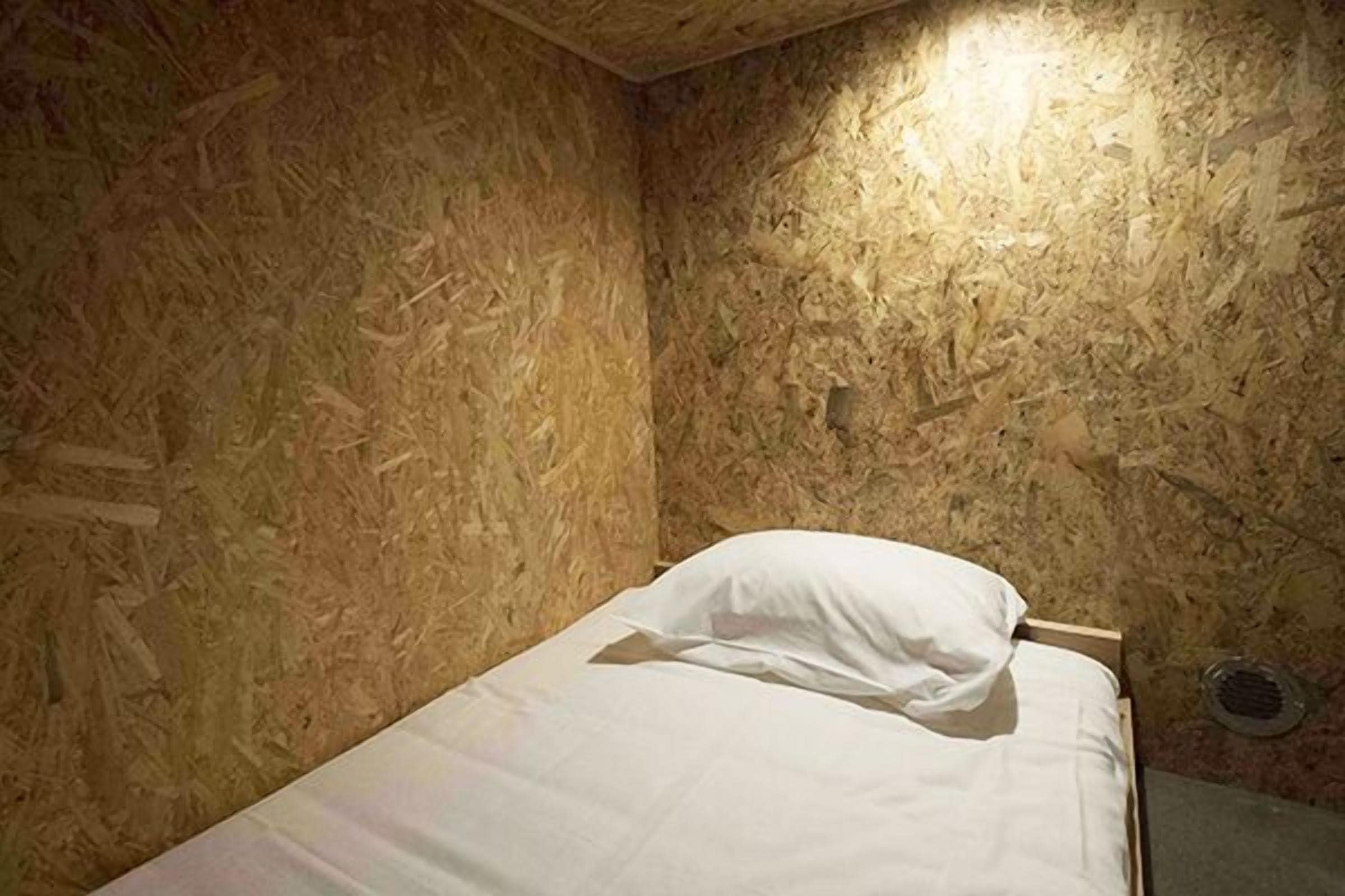 Una cama individual en una habitación con paredes de madera y techo inclinado.