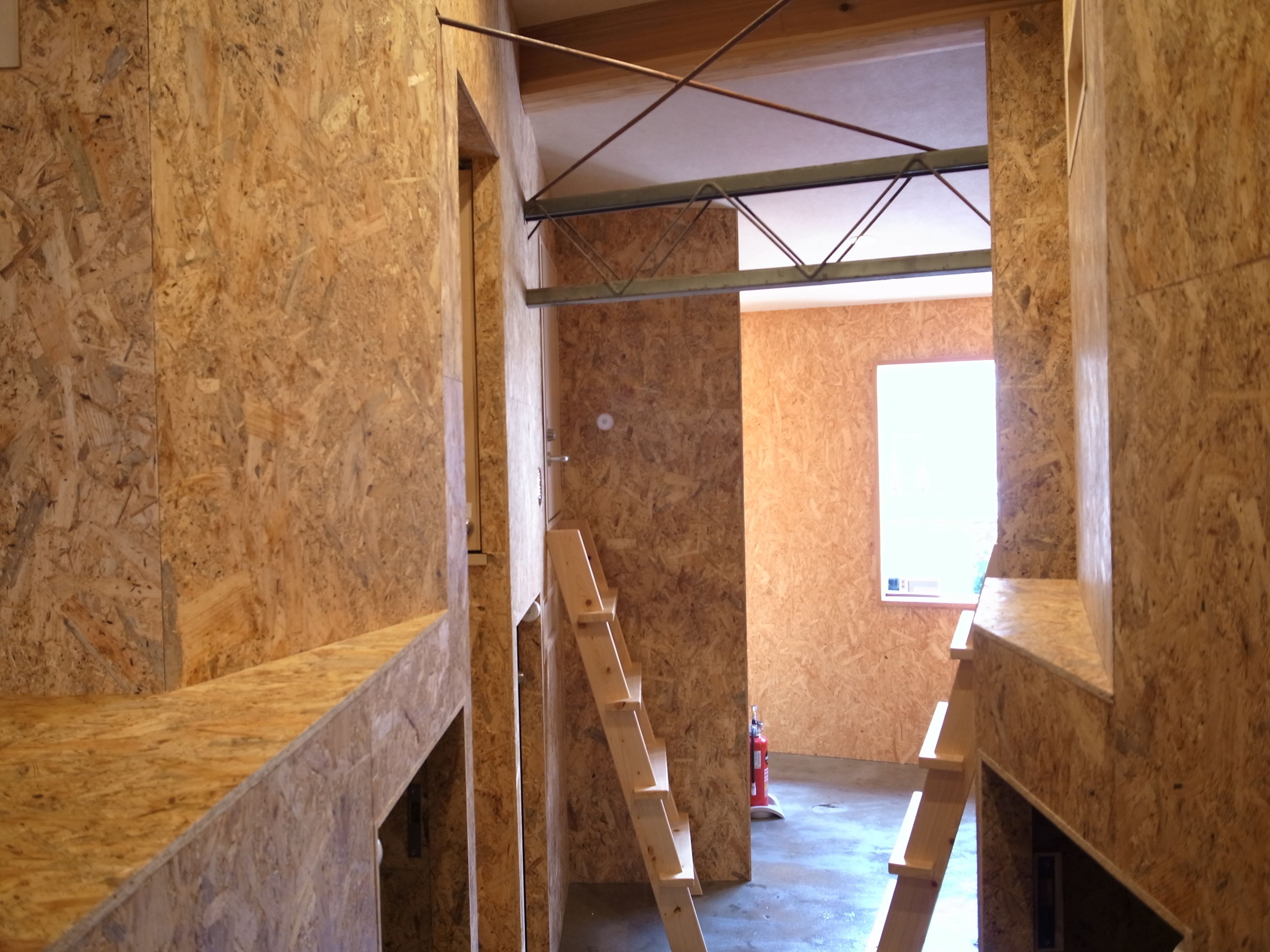 An unfinished room with exposed wooden walls and a ladder.