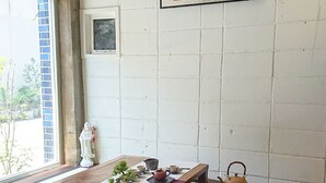 Een traditionele Japanse kamer met tatami vloerbedekking, een lage tafel met theeaffiche en een hangend bord met Japanse karakters.