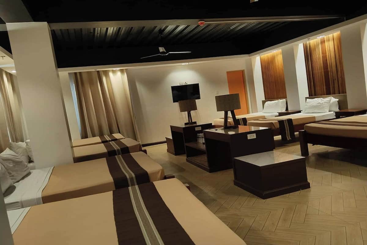 Una habitación de hotel con varias camas, televisión y ventilador de techo.