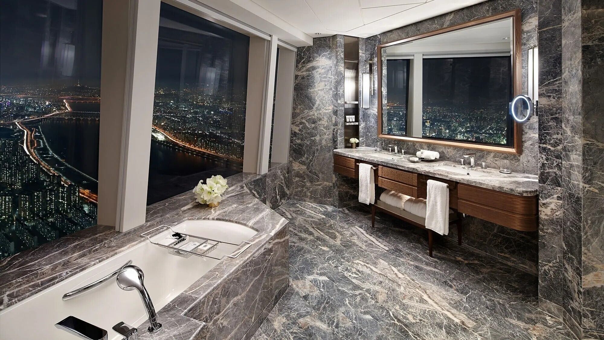 A modern bathroom with a large mirror, two sinks, and a bathtub.