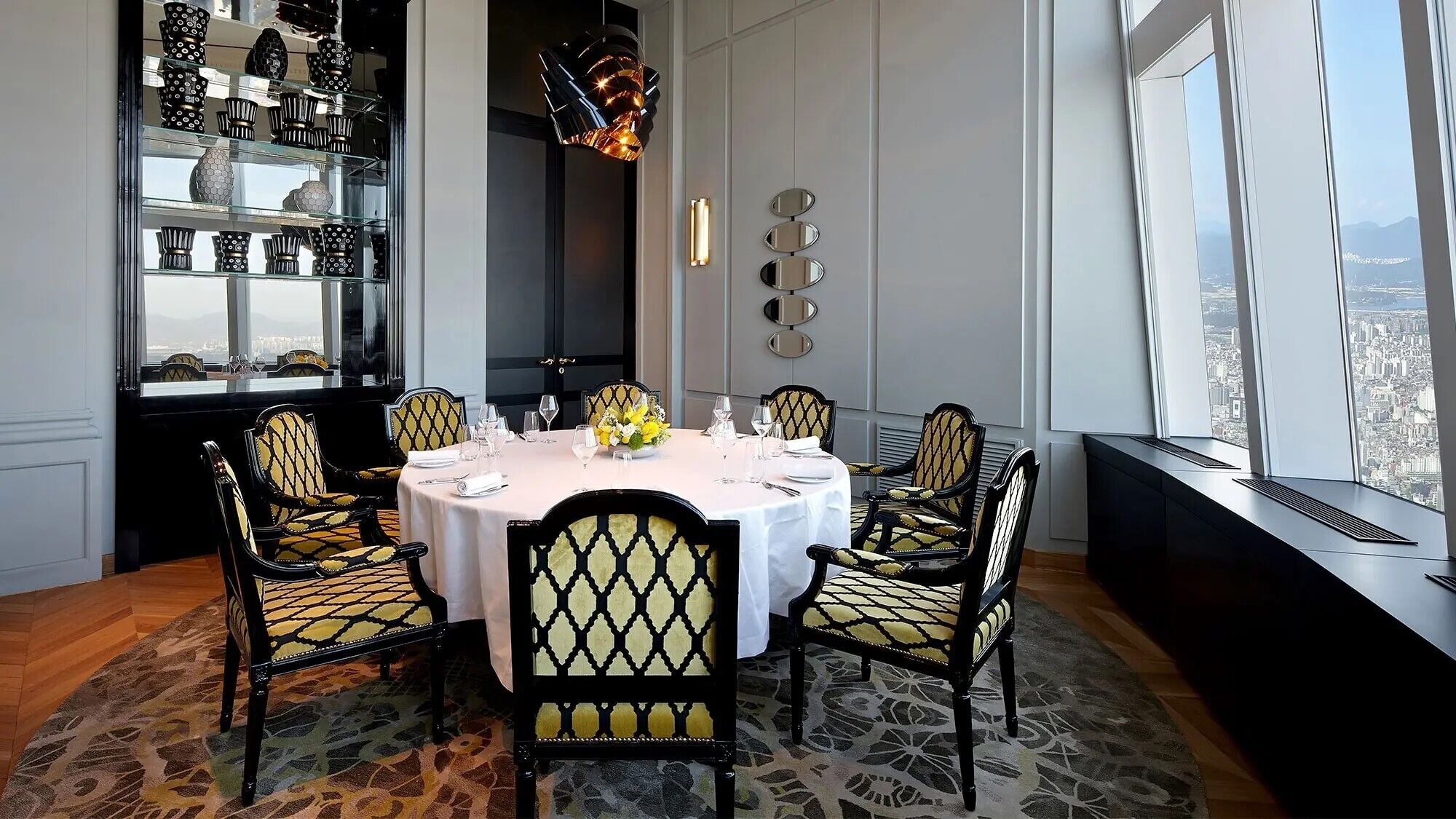 A dining area with a round table set for four, surrounded by patterned chairs.