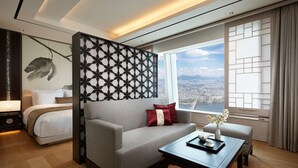 Una habitación de hotel moderna con cama, sofá y vistas a un paisaje urbano.