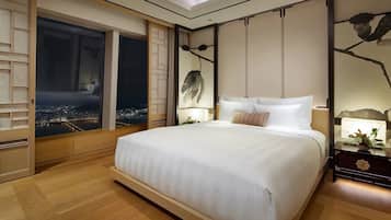 Une chambre moderne avec un grand lit, une vue nocturne sur le paysage urbain et un mur décoratif orné de motifs représentant des branches.