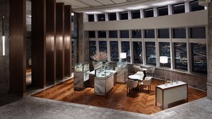 Un interior moderno con suelo de madera en patrón de espiga, encimeras de mármol y vistas a la ciudad a través de grandes ventanales.