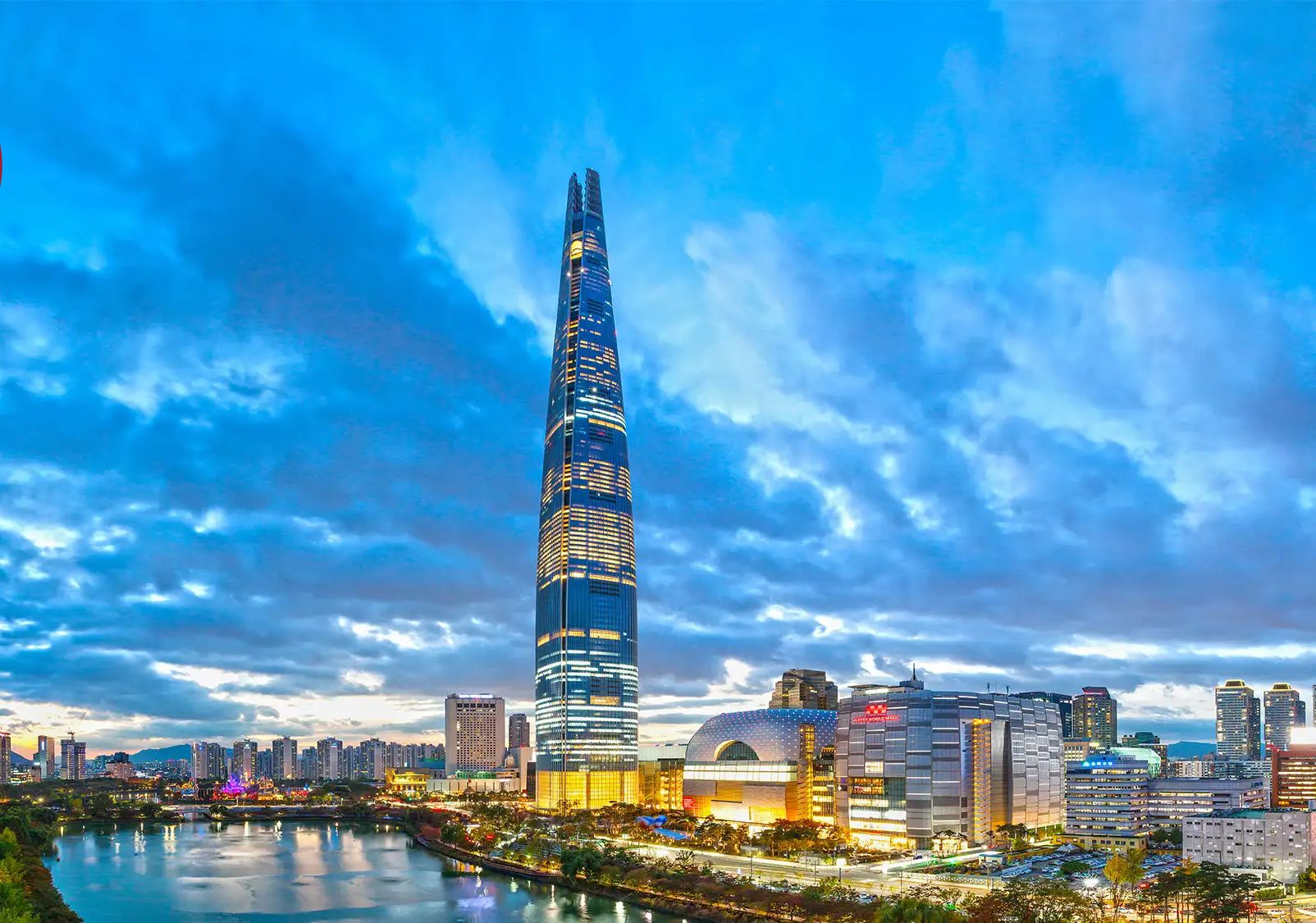 A modern skyscraper with a unique twisted design, surrounded by a cityscape with various buildings and a river.