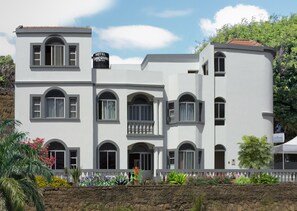 A multi-story hotel with a white facade, arched windows, and a balcony.