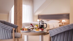 Une chambre d’hôtel avec un plateau de petit-déjeuner comprenant une cafetière, des croissants, des fraises et une assiette de fruits.