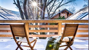 Une terrasse en bois avec deux chaises en bois, une couverture et une clôture en bois.