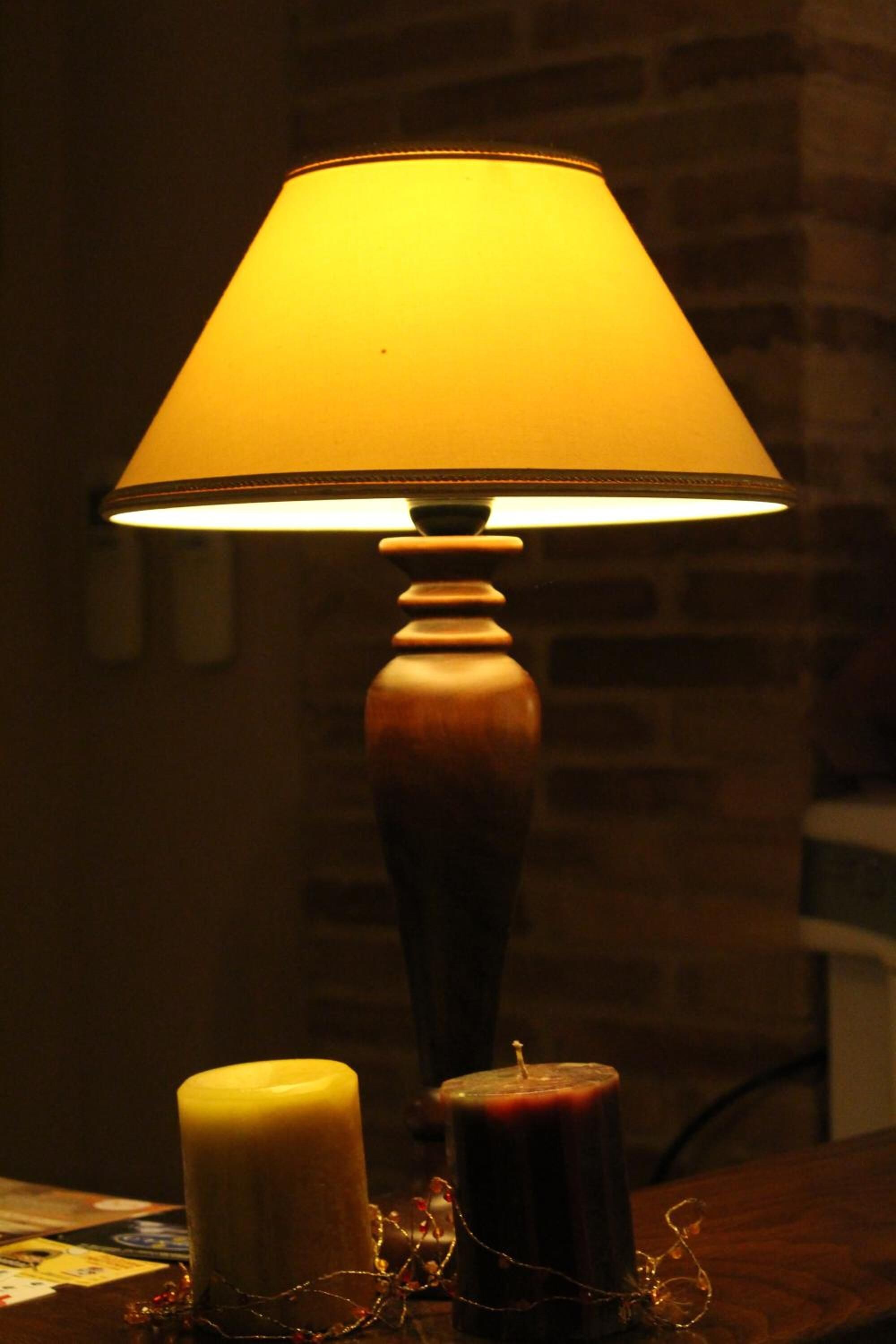 Una mesa con una lámpara, dos velas y una guirnalda decorativa.