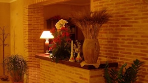 Una habitación acogedora con chimenea de ladrillo, una lámpara y varios objetos decorativos, como un jarrón y plantas.