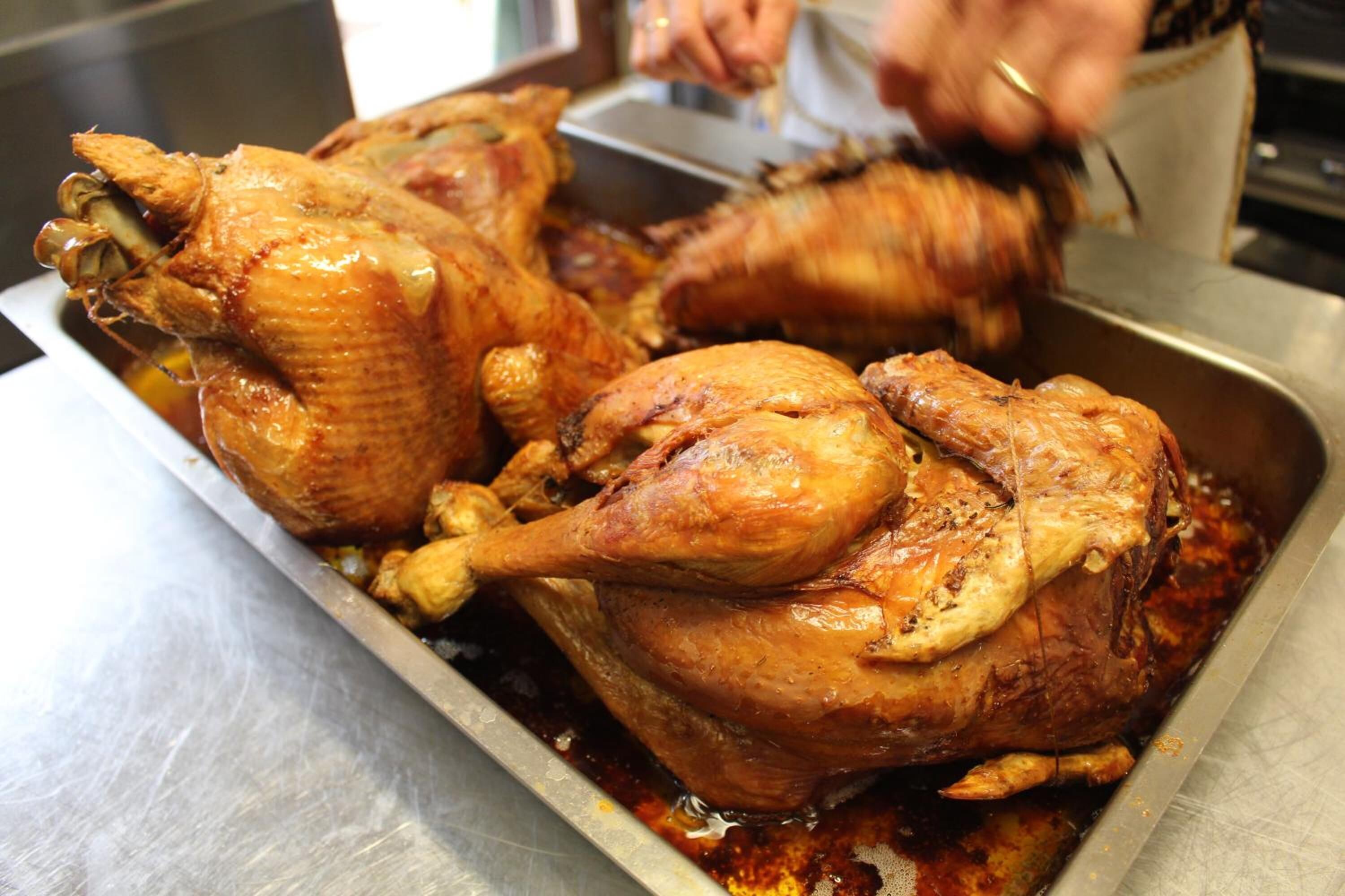 Un pavo entero asado en una bandeja metálica, probablemente en una cocina o zona de preparación.