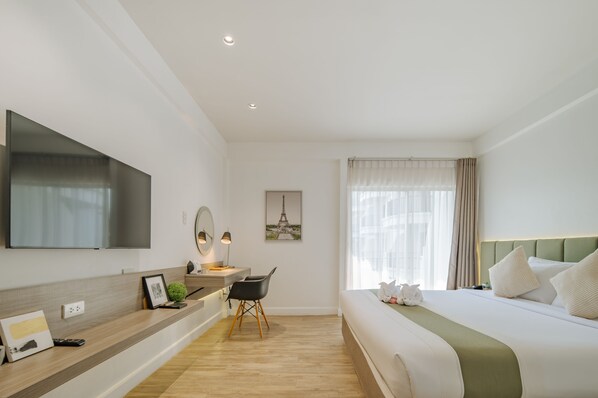 A modern hotel room with a large bed, a desk with a chair, a flat-screen TV, and a picture of the Eiffel Tower on the wall.