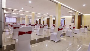 A spacious hall with rows of white chairs adorned with red sashes, arranged for an event.