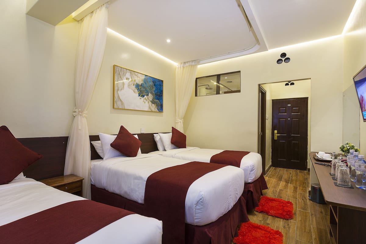 Habitación de hotel con dos camas, un escritorio con detalles, un cuadro y una puerta.