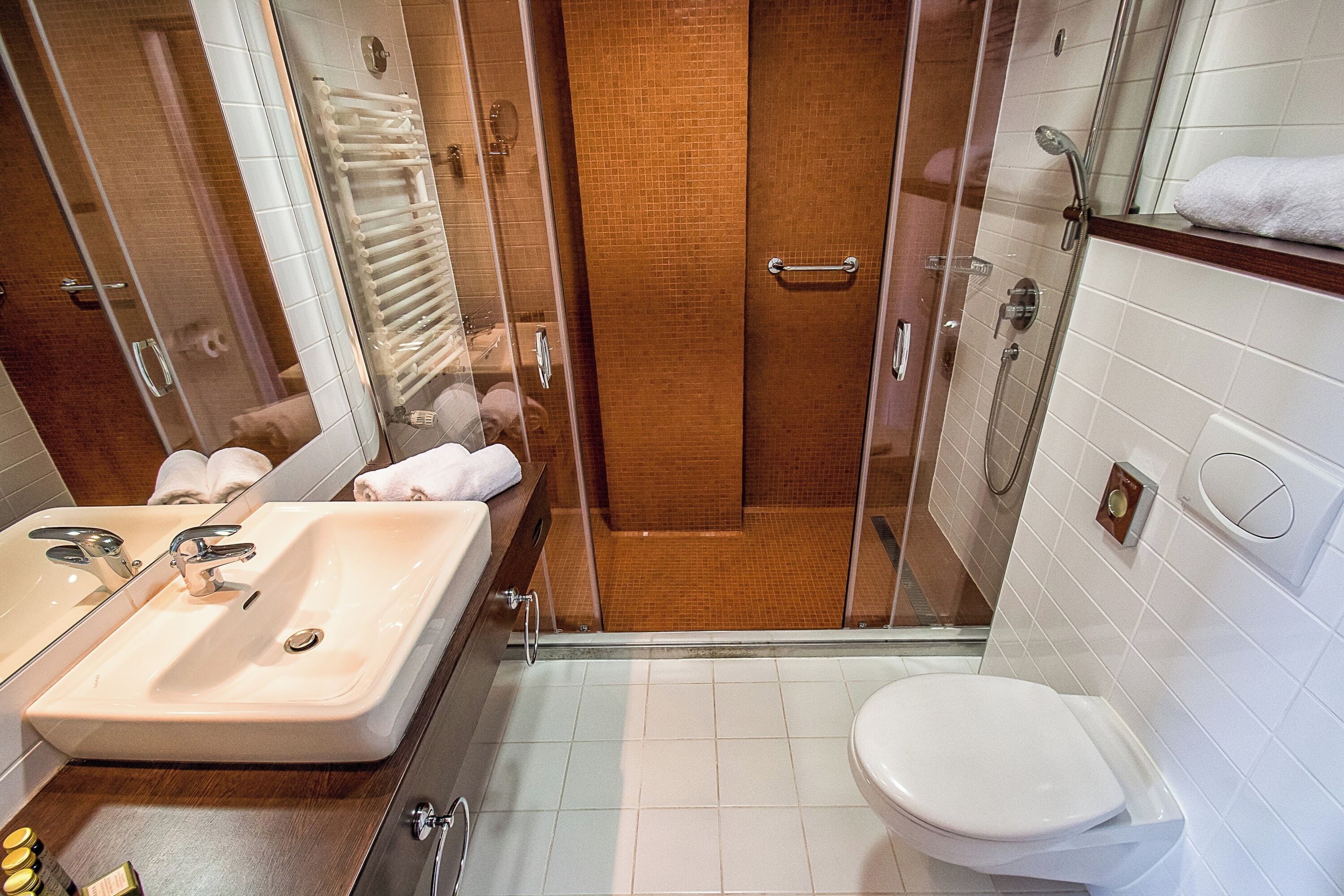 A modern bathroom with a glass-enclosed shower, a sink with a mirror, and a toilet.