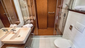 A modern bathroom with a glass-enclosed shower, a sink with a mirror, and a toilet.