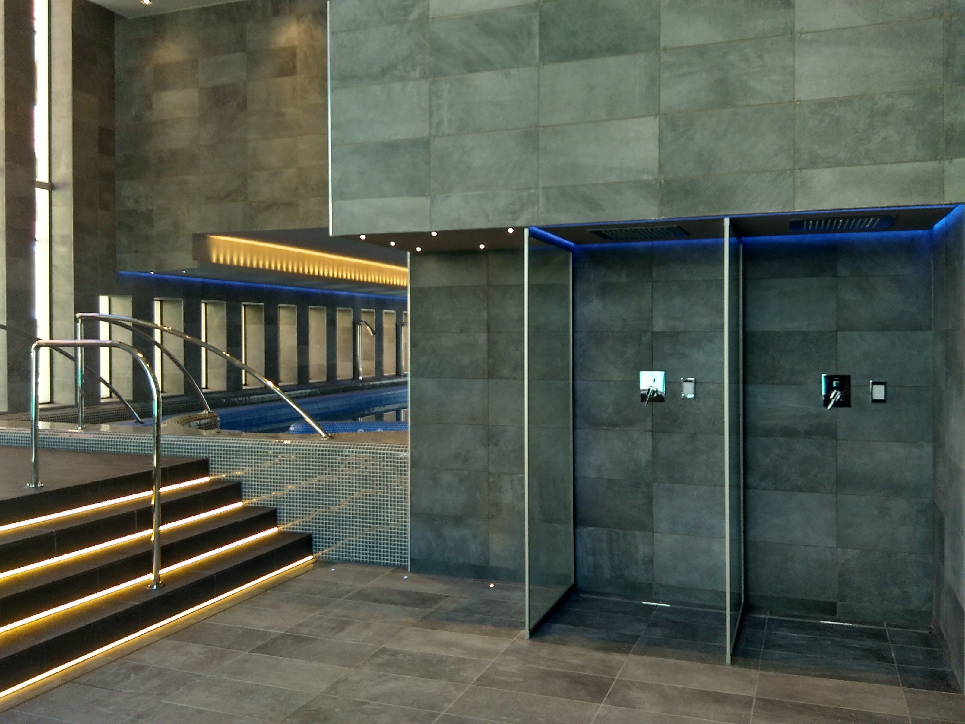 A modern elevator with a glass enclosure and a metal handrail.