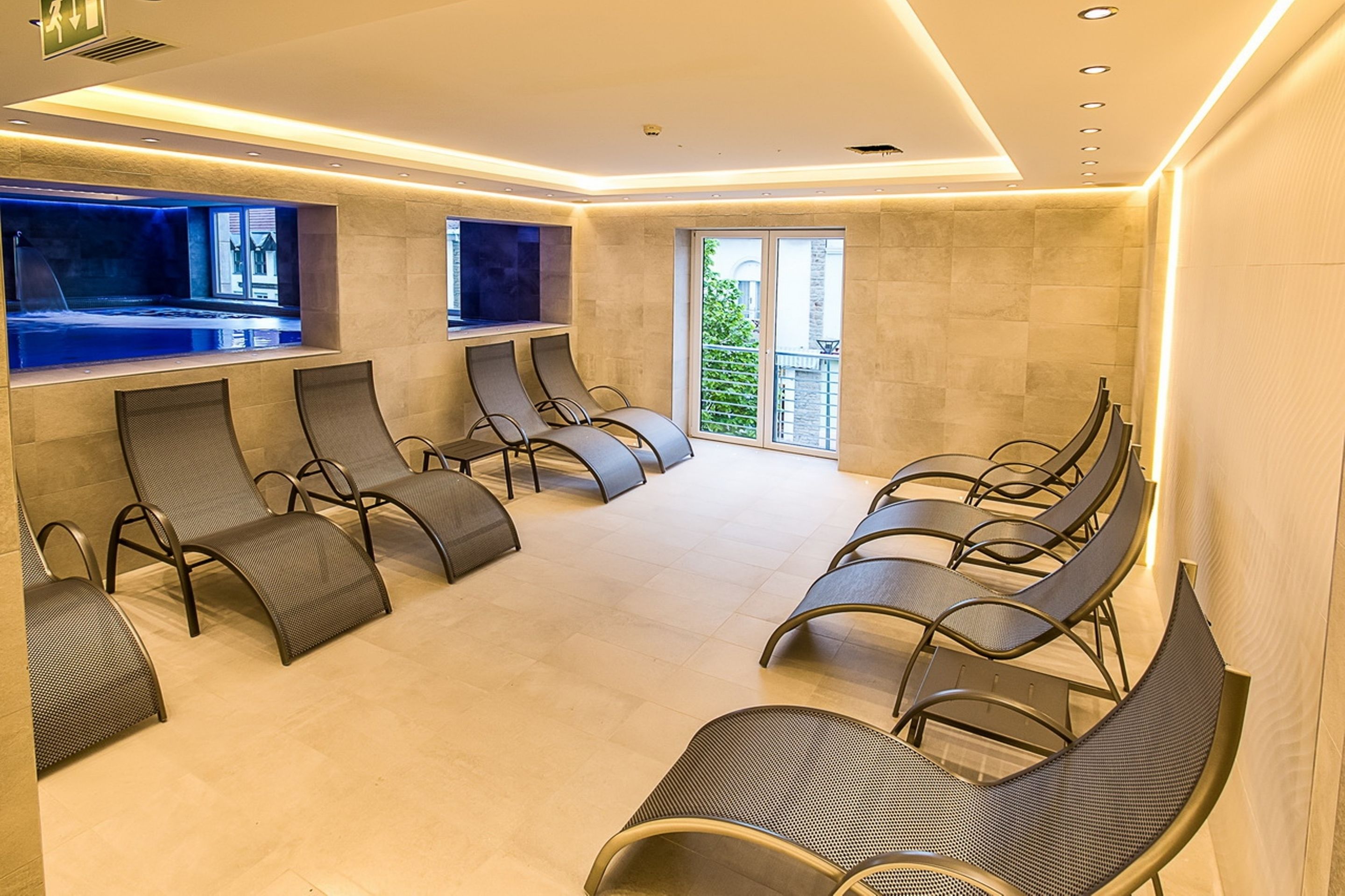 Un área de spa con varias sillas de masaje dispuestas en filas, un ventanal y vistas al exterior.