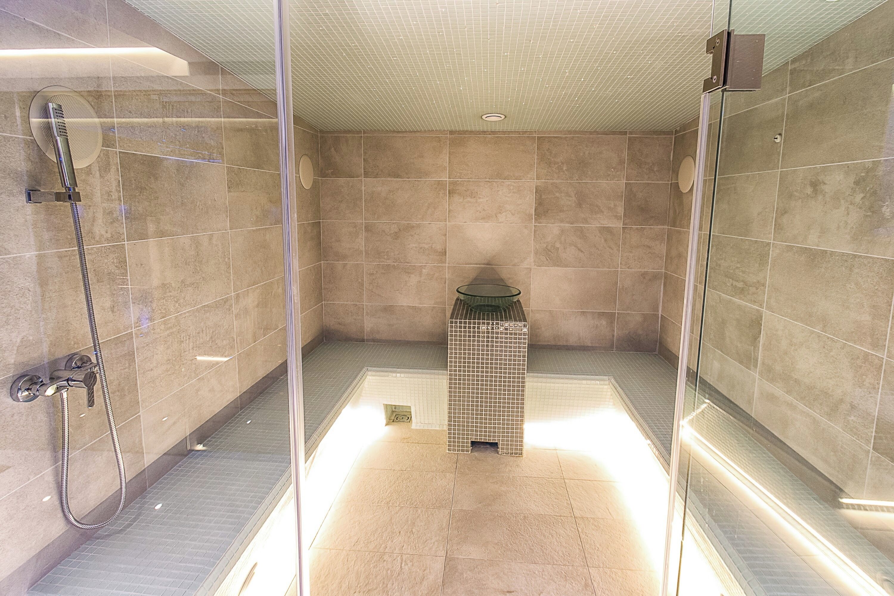 Ein modernes Duschbad mit Glasabtrennung, Handbrause und Fliesenboden.