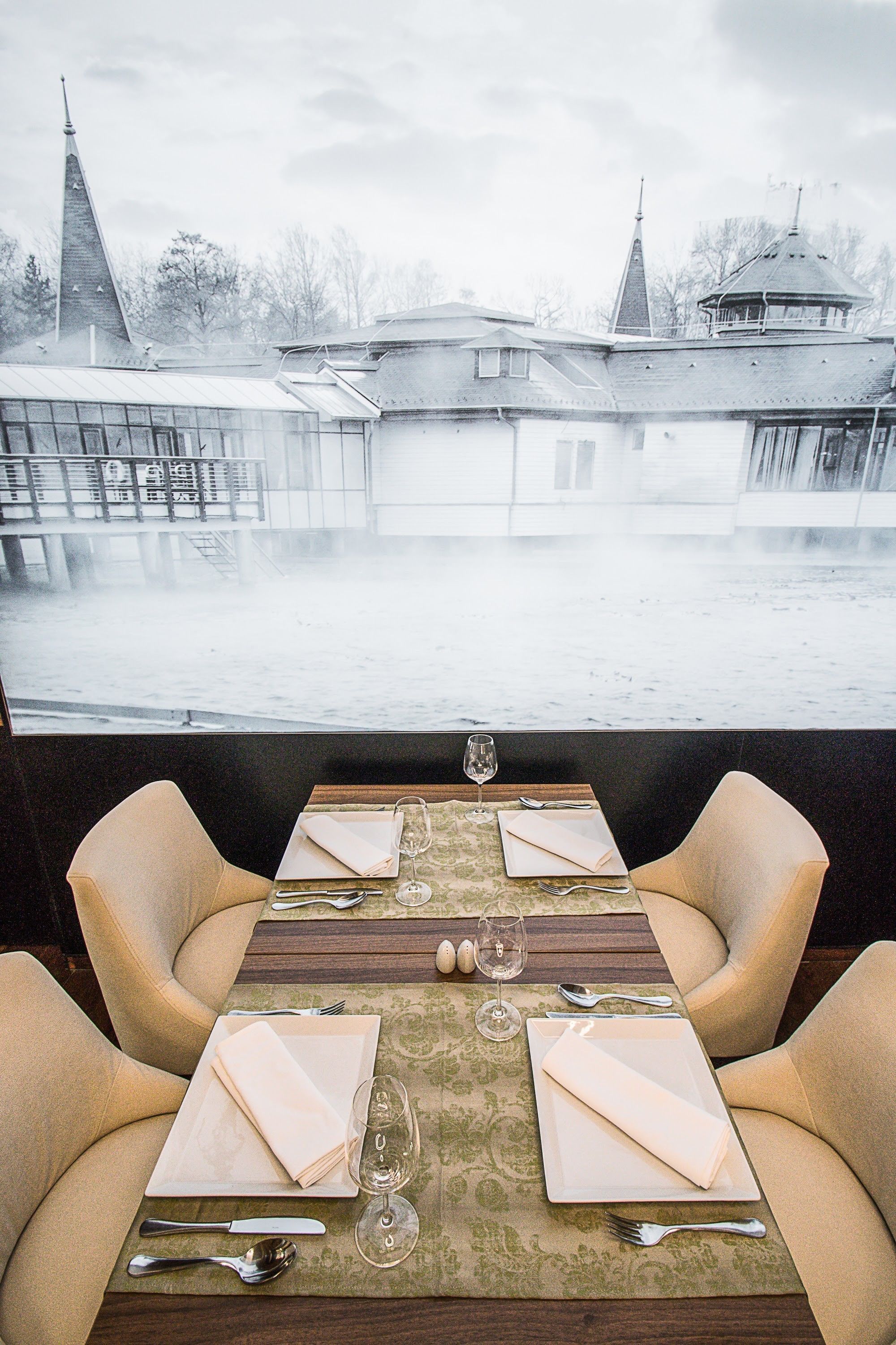 A dining table set for four with a view of a waterfront and buildings in the background.