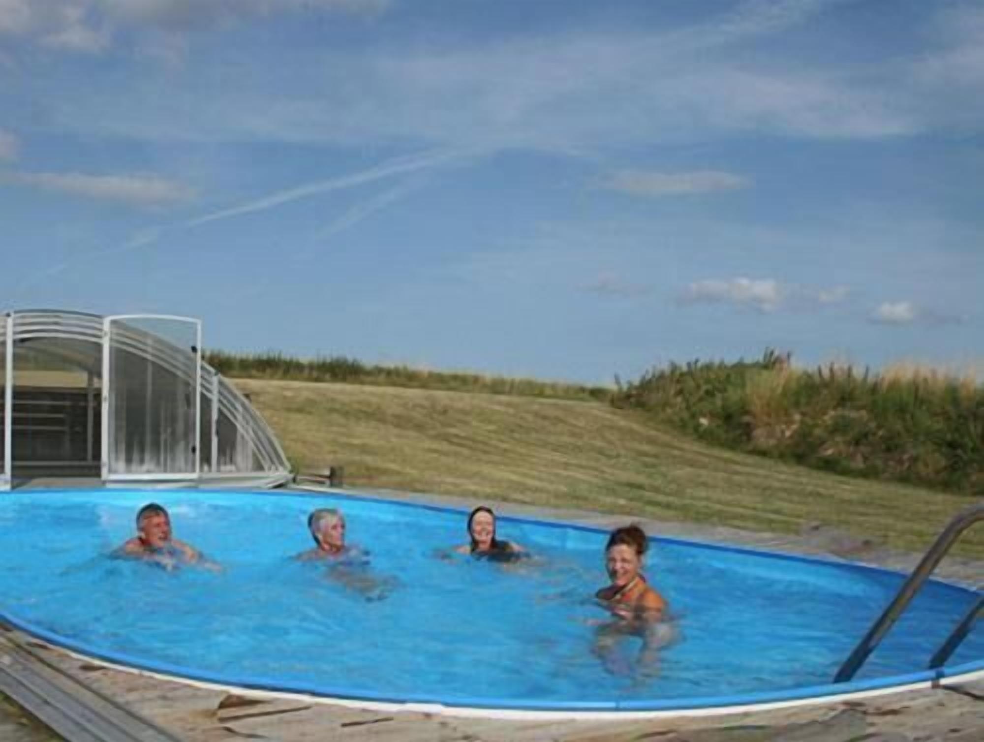 A swimming pool with a clear sky and grassy area in the background.