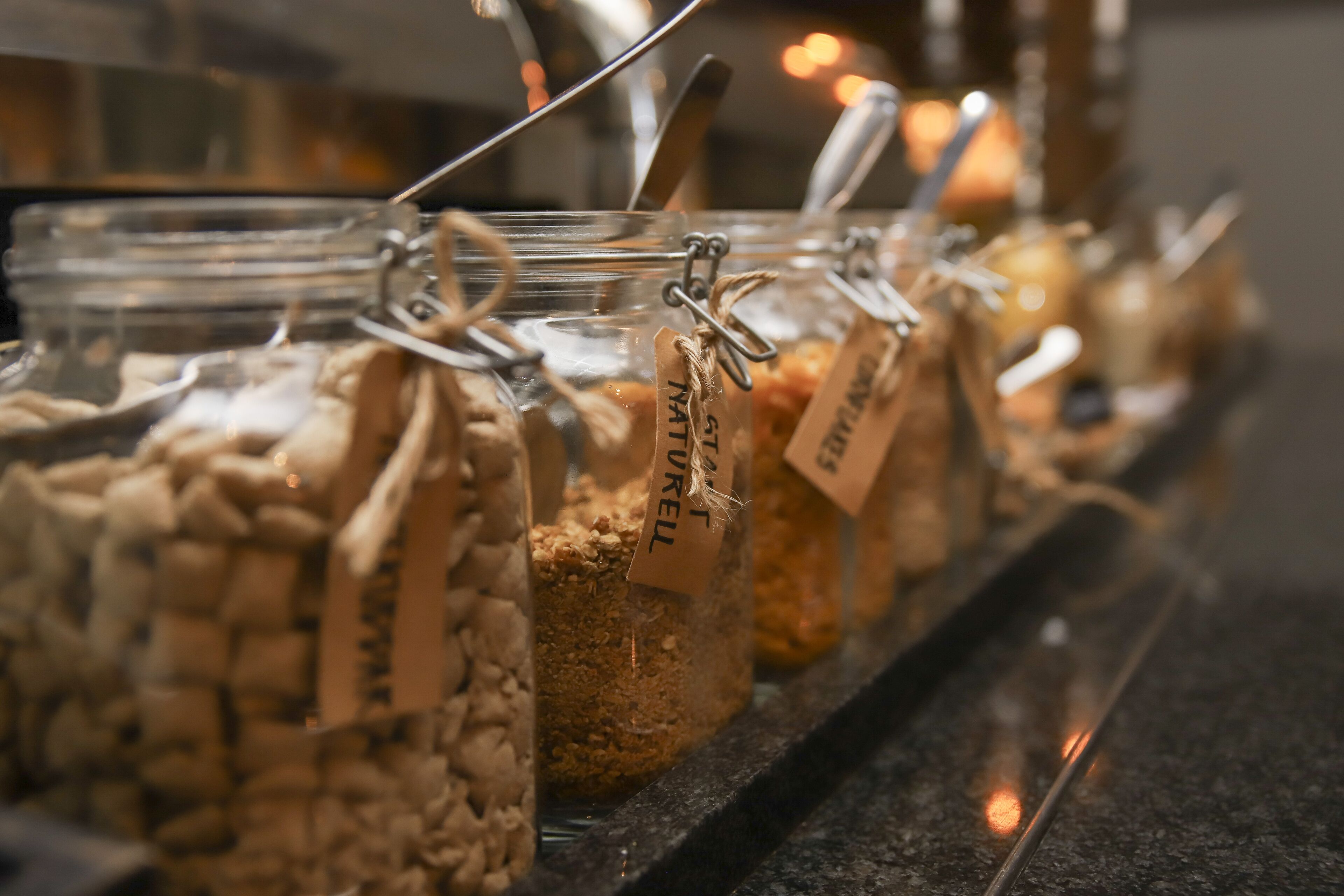 Glass jars with labels, possibly containing food items, arranged on a shelf.