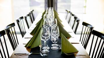 Een eettafel gedekt met verschillende wijnglazen en groene servetten, omringd door zwarte stoelen.