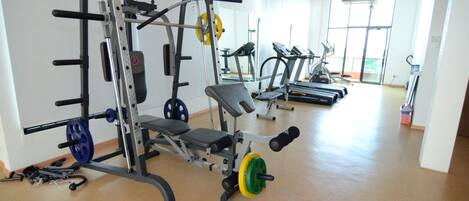 A gym with weightlifting equipment, treadmills, and a bench.