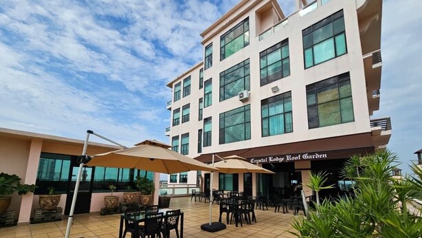 An outdoor patio area with tables and chairs, umbrellas, and potted plants. - Crystal Lodge (Kota Bharu)