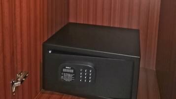 Una caja fuerte negra con teclado numérico, orificio para llave y un pequeño estante encima.