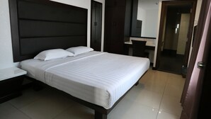 A hotel room with a large bed, a bedside table, a wardrobe, a mirror, and a bathroom visible through an open door. - Crystal Lodge (Kota Bharu)
