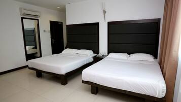 A hotel room with two single beds, a mirror, an air conditioning unit, and a door.