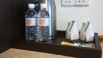 Eine Arbeitsplatte mit zwei Crystal Lodge Wasserflaschen, einem silbernen Wasserkocher und drei weißen Tassen.