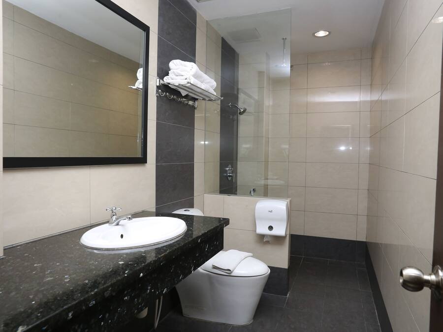Un baño moderno con lavamanos, espejo, toallero, ducha e inodoro.